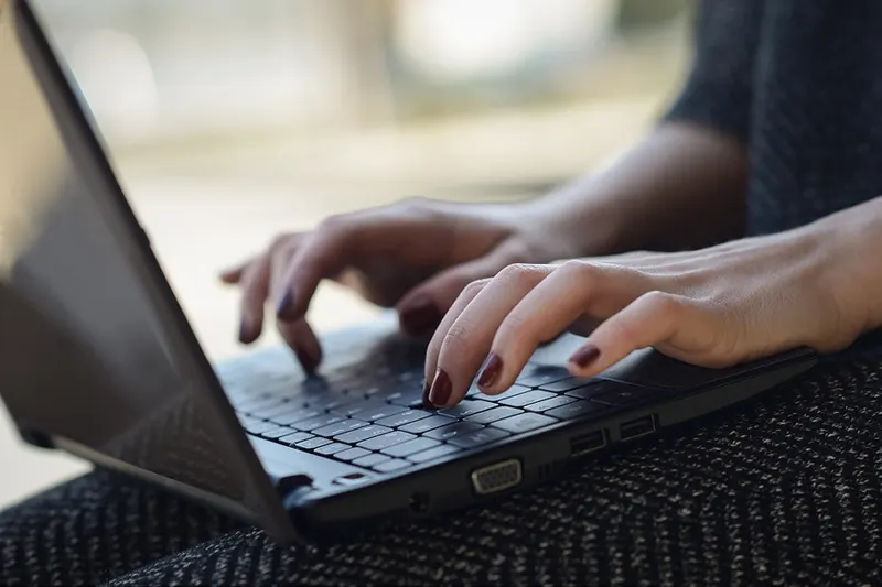 woman's hands typing on  laptop